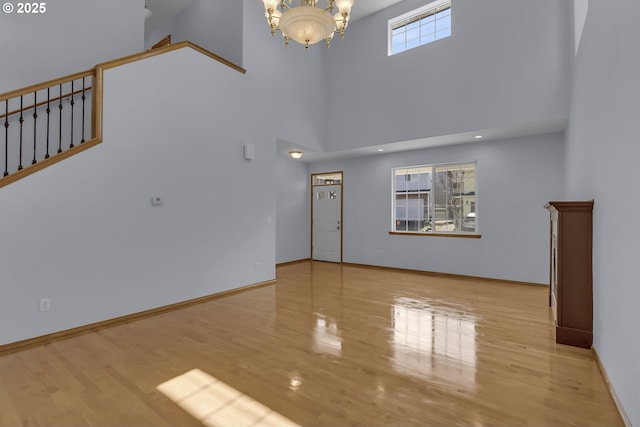 13007 SE Raymond Ct, Portland, OR 97236 - unfurnished living room featuring a high ceiling, a chandelier, wood finished floors, stairs, and baseboards