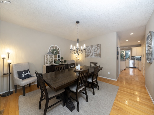 dining area with light wood-type flooring, baseboards, and a chandelier