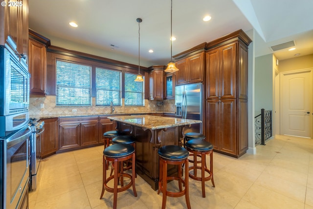 703 SE Keel Ave, Lincoln City, OR 97367 - kitchen with visible vents, a breakfast bar area, light stone countertops, stainless steel appliances, and a sink