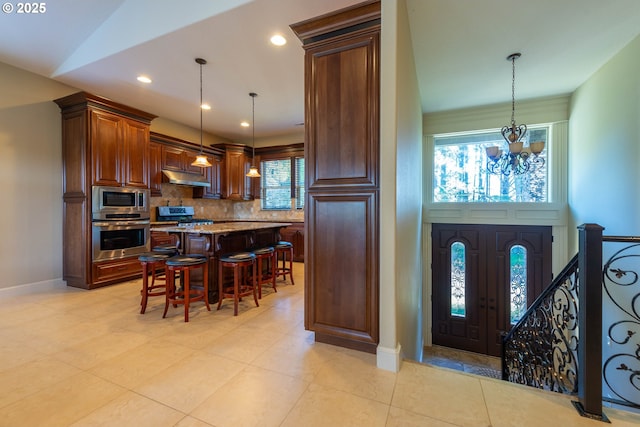 703 SE Keel Ave, Lincoln City, OR 97367 - kitchen with a chandelier, under cabinet range hood, stainless steel appliances, a kitchen breakfast bar, and backsplash