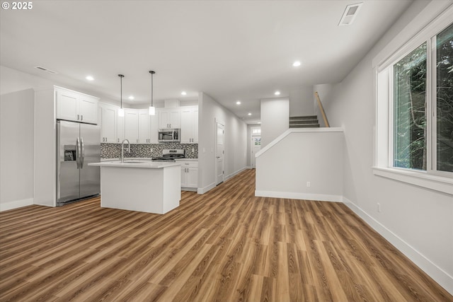 12141 SE Knapp Ln, Portland, OR 97266 - kitchen with appliances with stainless steel finishes, light countertops, tasteful backsplash, light wood-type flooring, and recessed lighting