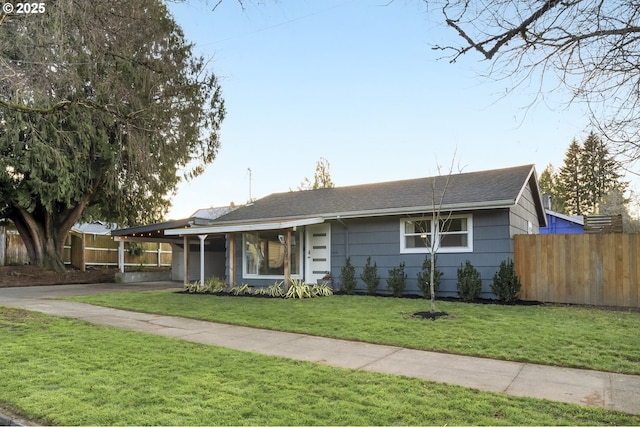 ranch-style house featuring driveway, an attached carport, a front lawn, and fence