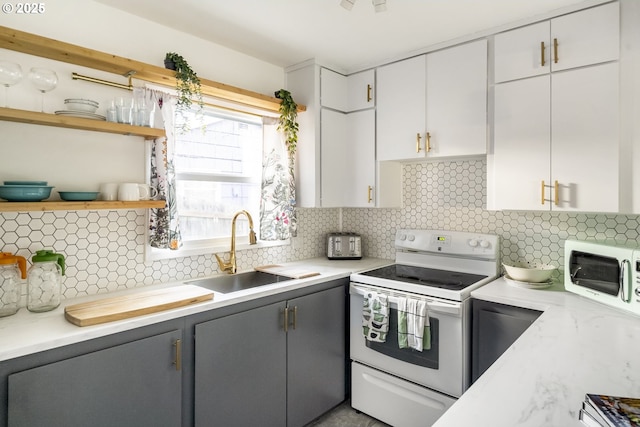 kitchen with gray cabinetry, white appliances, a sink, open shelves, and tasteful backsplash