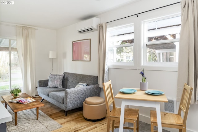 sitting room with light wood-type flooring, a wall mounted air conditioner, and visible vents