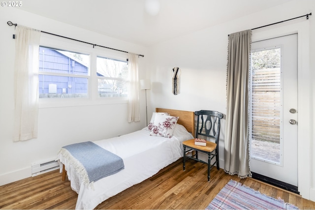 bedroom with a baseboard radiator, multiple windows, and wood finished floors