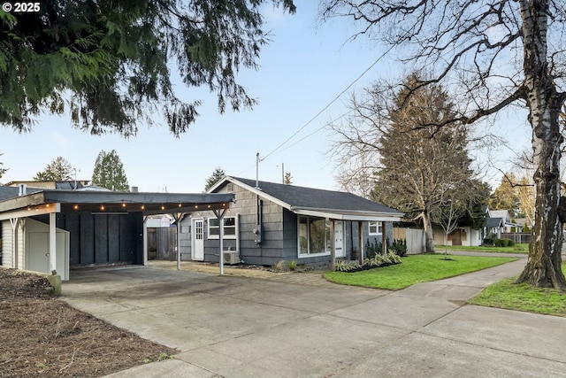 view of front of home featuring driveway, fence, a front lawn, and a carport