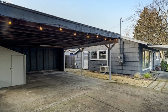 view of vehicle parking featuring a carport, a storage unit, ac unit, and driveway