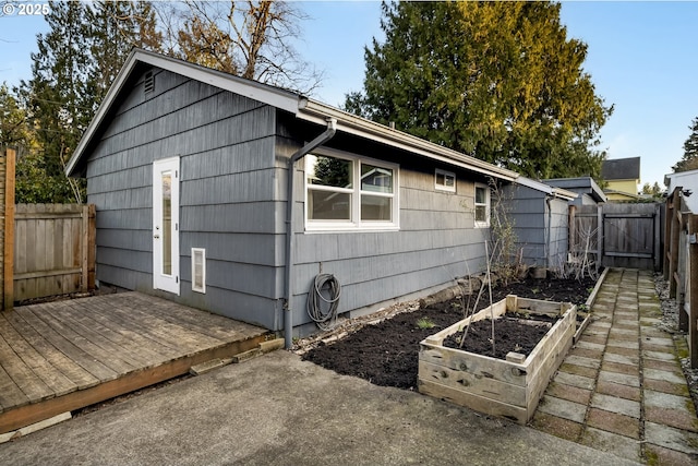 view of side of home with a garden, a fenced backyard, and a wooden deck