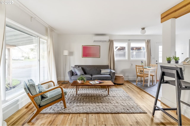 living area with a wall mounted AC, wood finished floors, and a healthy amount of sunlight