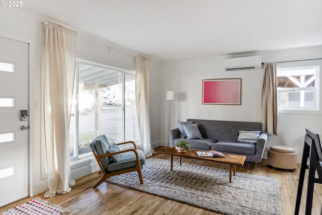 living area with light wood finished floors, baseboards, and an AC wall unit