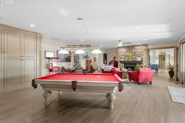 game room featuring ceiling fan, a stone fireplace, light wood-type flooring, and billiards