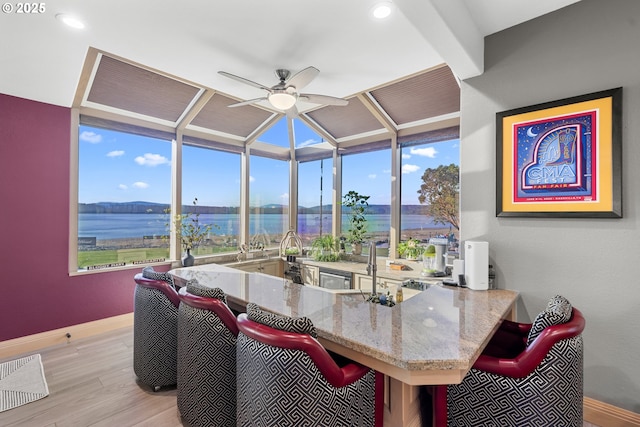 dining room with lofted ceiling with beams, a water view, ceiling fan, and light hardwood / wood-style flooring