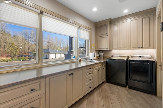 clothes washing area with cabinets, independent washer and dryer, sink, and light wood-type flooring