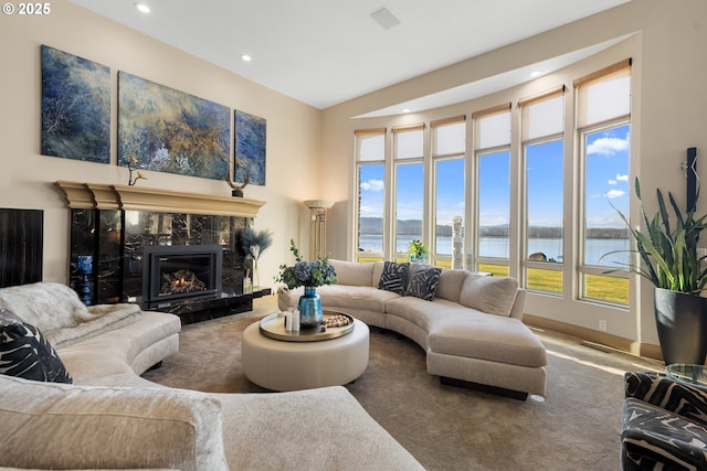 living room with carpet floors, a high end fireplace, and a water view