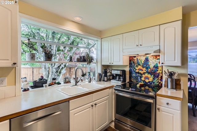 4730 SW 189th Pl, Beaverton, OR 97078 - kitchen with light countertops, under cabinet range hood, white cabinets, a sink, and stainless steel appliances