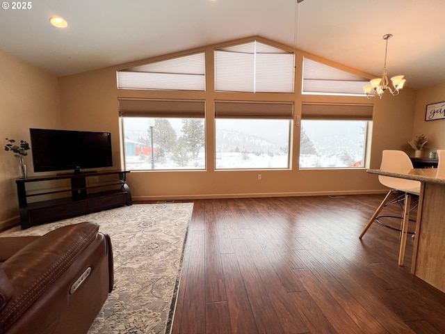 living room featuring dark hardwood / wood-style flooring, vaulted ceiling, and a notable chandelier