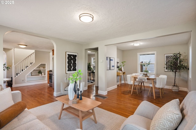 living room featuring hardwood / wood-style flooring, built in shelves, and a textured ceiling