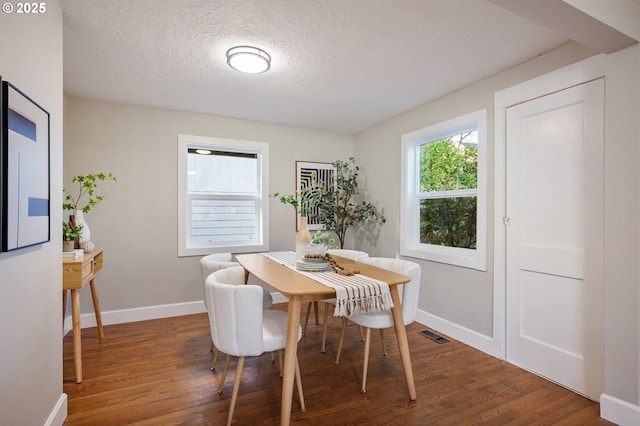 dining space featuring a textured ceiling and hardwood / wood-style flooring