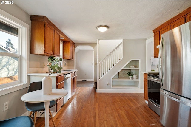 kitchen featuring built in shelves, light wood-type flooring, appliances with stainless steel finishes, and sink