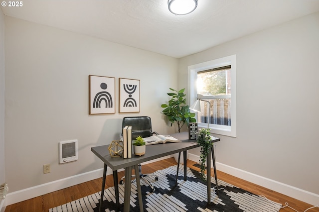 office featuring heating unit and hardwood / wood-style flooring