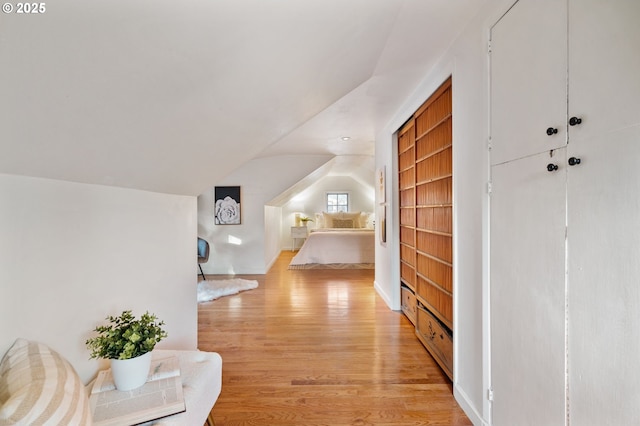 corridor with light hardwood / wood-style flooring and lofted ceiling