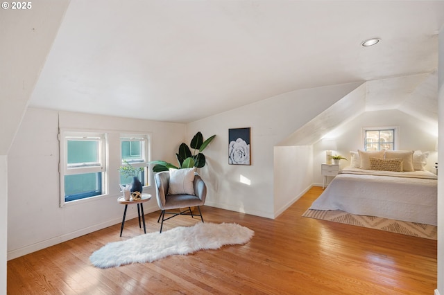 bedroom with light wood-type flooring, vaulted ceiling, and multiple windows