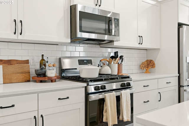 kitchen featuring white cabinets, stainless steel appliances, decorative backsplash, and light countertops