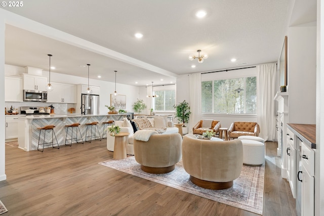 living area with recessed lighting, light wood-type flooring, and an inviting chandelier