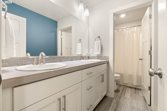 bathroom featuring double vanity, toilet, a shower with curtain, and a sink