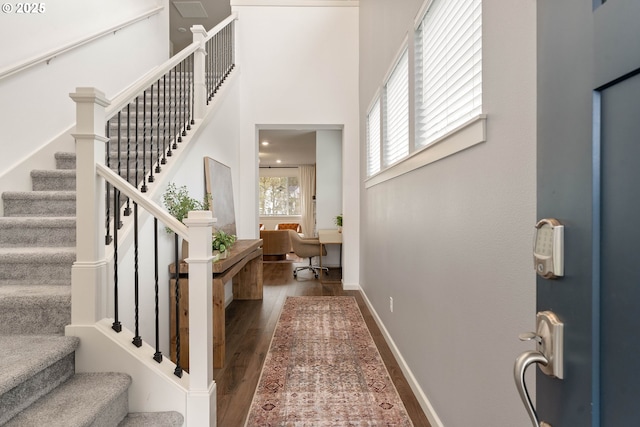 foyer entrance with stairs, a high ceiling, baseboards, and wood finished floors