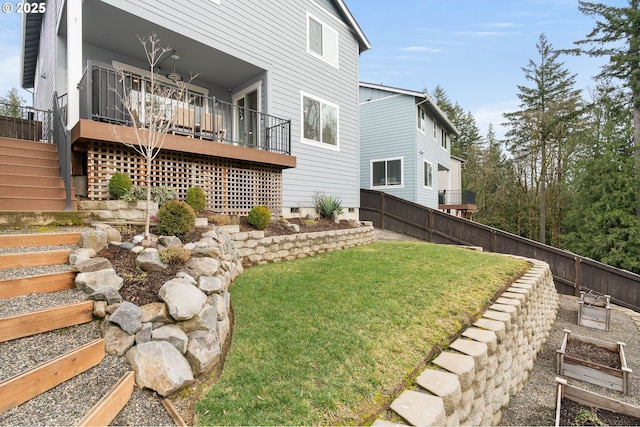 view of yard with a fenced backyard, a wooden deck, a garden, and stairway