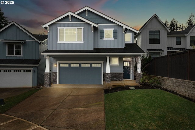 craftsman-style house featuring board and batten siding, driveway, a lawn, fence, and an attached garage