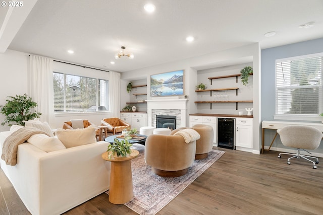 living area with recessed lighting, wine cooler, wood finished floors, and a fireplace