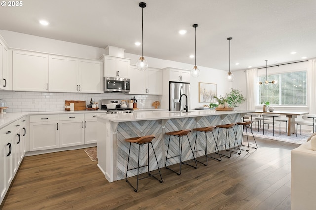 kitchen featuring light countertops, decorative backsplash, stainless steel appliances, and dark wood-style floors