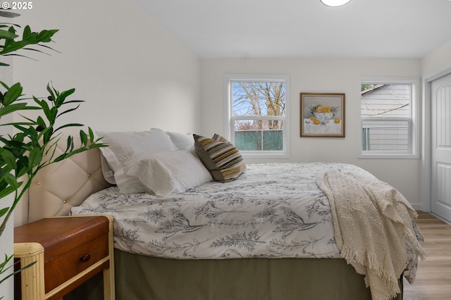 bedroom with multiple windows and light wood-style floors