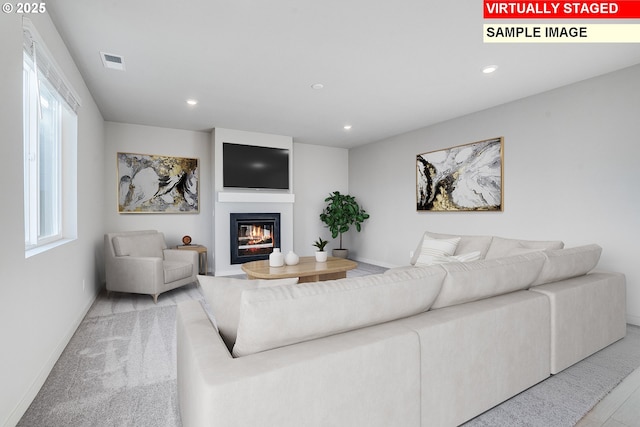 living room with a wealth of natural light, a glass covered fireplace, visible vents, and recessed lighting