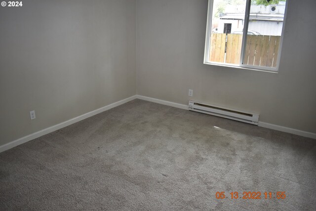 spare room with a baseboard heating unit, carpet, and plenty of natural light