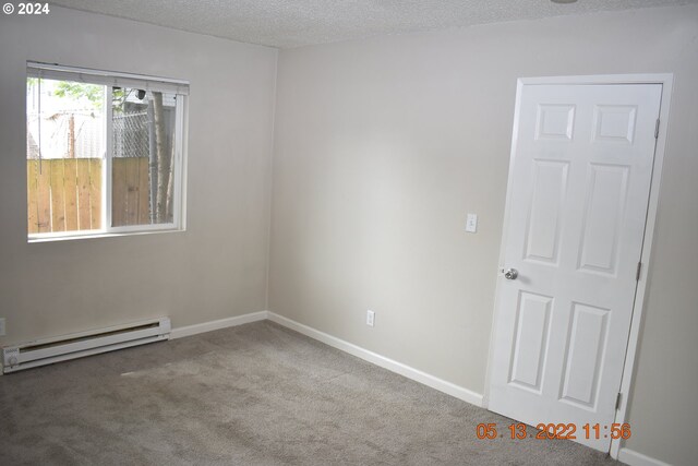 carpeted spare room featuring baseboard heating and a textured ceiling