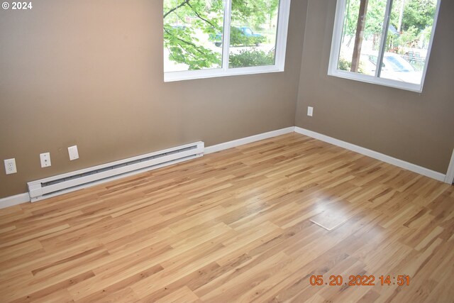 empty room with a baseboard heating unit and light hardwood / wood-style floors