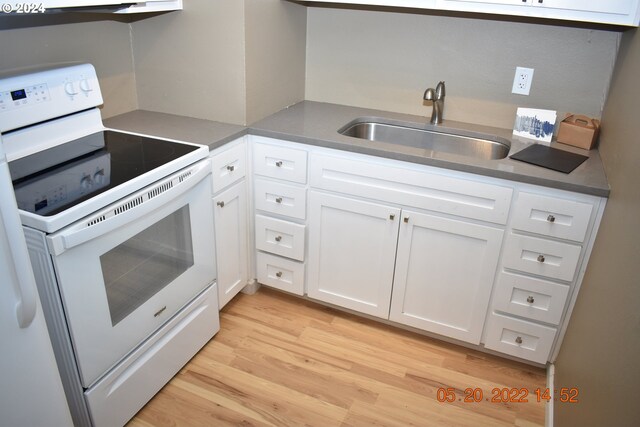 kitchen with sink, white cabinetry, light hardwood / wood-style floors, and white electric range oven