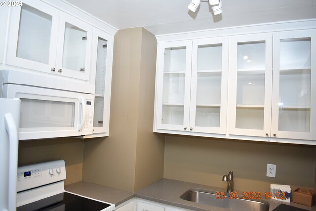 kitchen with white appliances, white cabinets, and sink