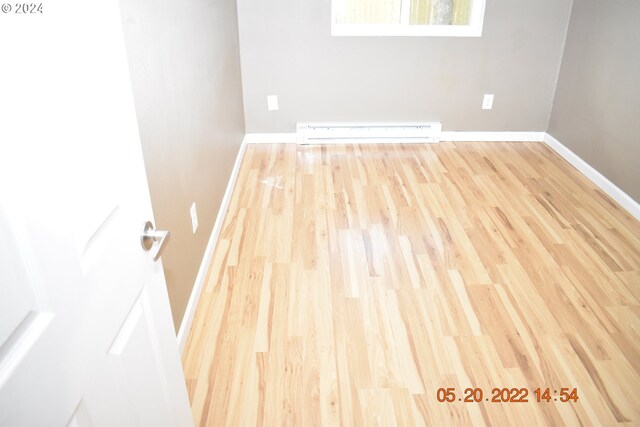 spare room with baseboard heating and wood-type flooring