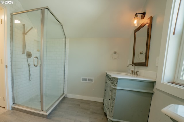 bathroom featuring visible vents, wood finished floors, a stall shower, and vanity