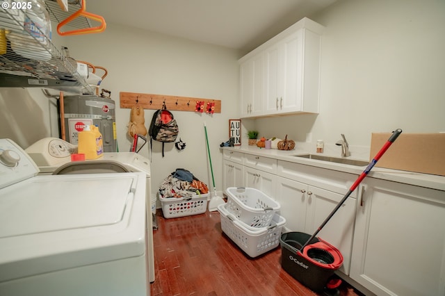 clothes washing area featuring strapped water heater, washing machine and dryer, cabinet space, wood finished floors, and a sink