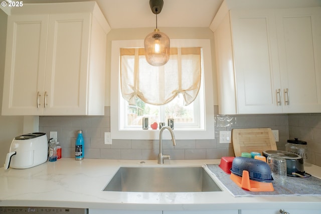 kitchen with a sink, white cabinetry, decorative backsplash, and light stone countertops