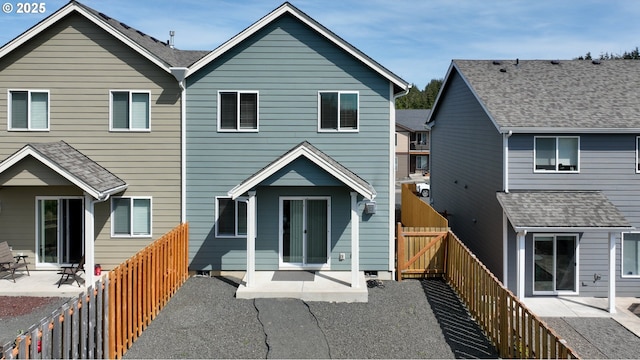 rear view of property featuring a fenced backyard, a patio area, and a gate