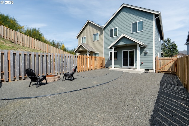 rear view of property featuring a fenced backyard, a patio, and a fire pit
