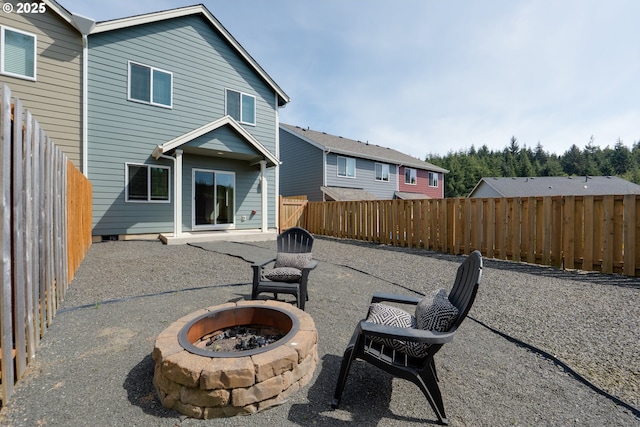 back of property with a fenced backyard, a patio, and a fire pit