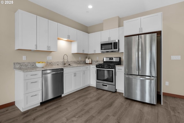 kitchen featuring white cabinets, baseboards, appliances with stainless steel finishes, and a sink