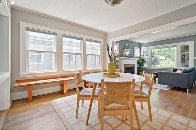 3620 NE 80th Ave, Portland, OR 97213 - dining area with light wood-type flooring, a fireplace, a textured ceiling, and baseboards